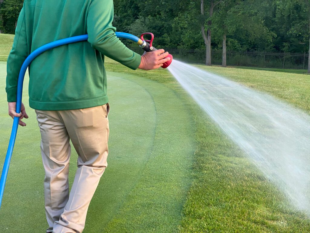 A golf course maintenance worker sprays on the greens.