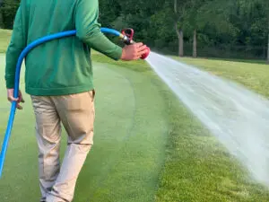 A golf course maintenance worker sprays on the greens.