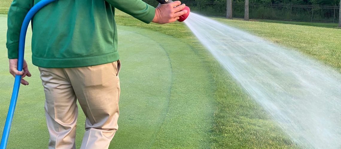 A golf course maintenance worker sprays on the greens.